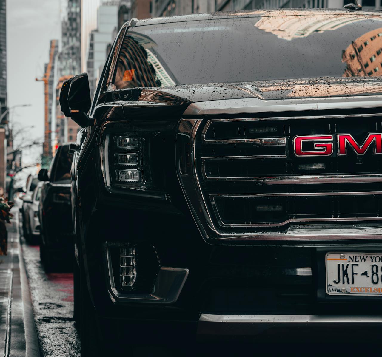 Black GMC vehicle parked on rainy New York City streets, showcasing urban lifestyle.