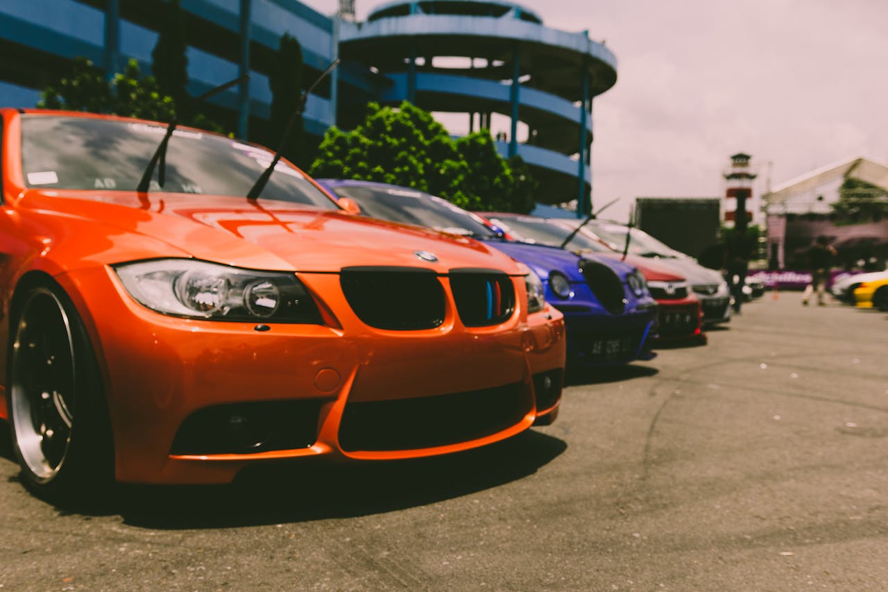 Close-up of vibrant sports cars parked outdoors, showcasing custom modifications and sleek designs.