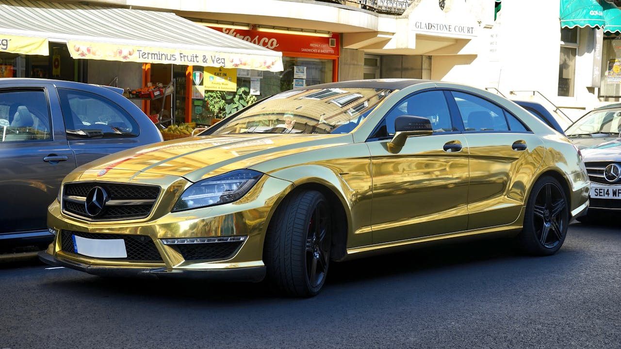 A gleaming gold Mercedes-Benz parked on a city street, reflecting urban elegance.